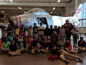 Students pose in front of a plane